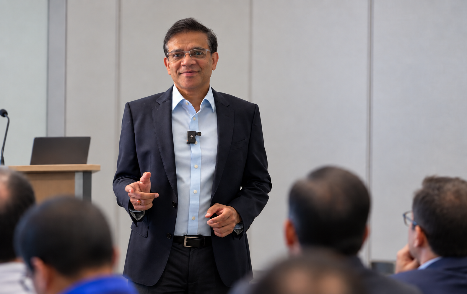 Anurag Gupta speaking to a seated audience of professionals in a conference room